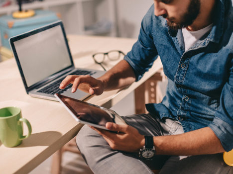 Image of an individual managing resources on devices like laptops and tablets.